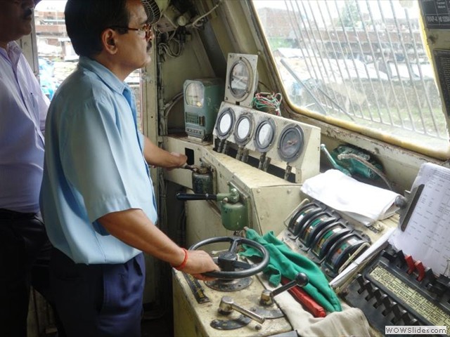 Loco pilot with one hand on master controller, another on Train Brake handle with Loco Inspector
